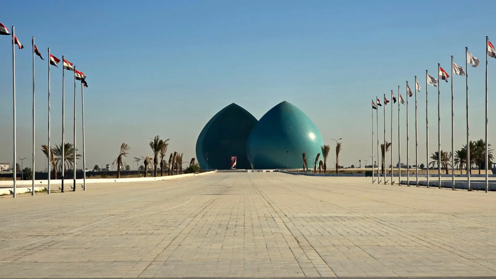 The Martyr Monument in Baghdad, Iraq, featuring its iconic split turquoise dome and reflecting pool, photographed during tour of Iraq.