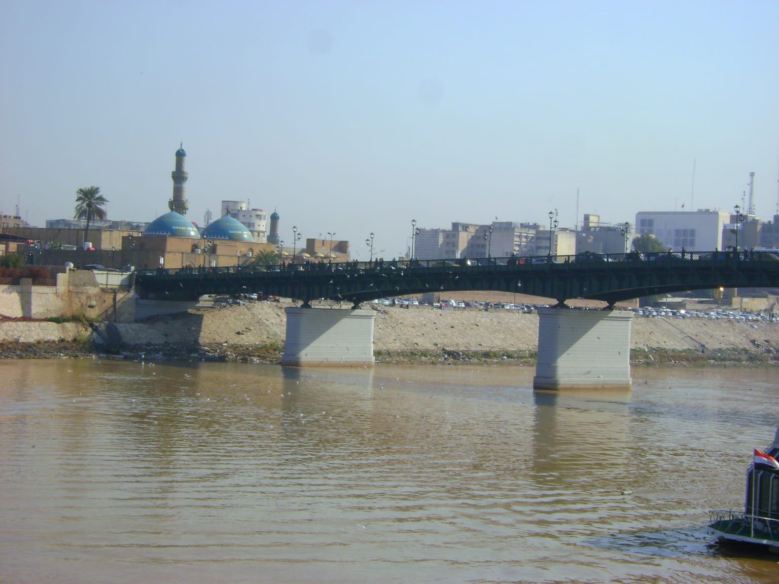 Scenic view of the Tigris River flowing through central Baghdad, Iraq, with the city's skyline and riverside promenade.