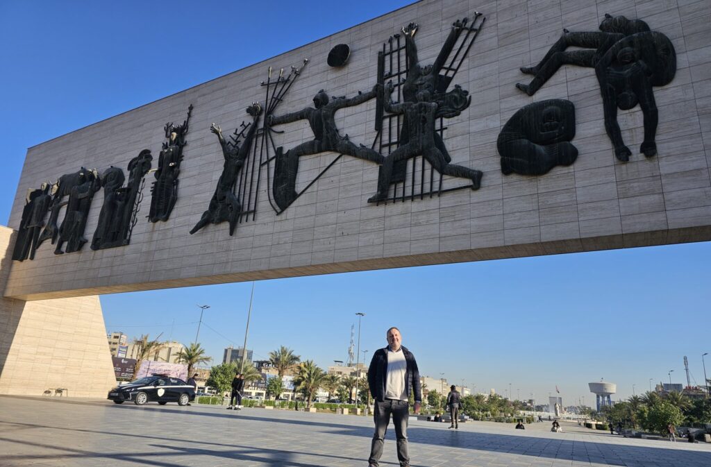 Tourist standing in front of the Freedom Monument (Nasb al-Hurriyah) at Liberation Square (Tahrir Square) in Baghdad, Iraq, one of the city's most iconic landmarks celebrating Iraq’s modern history, culture, and artistic heritage
