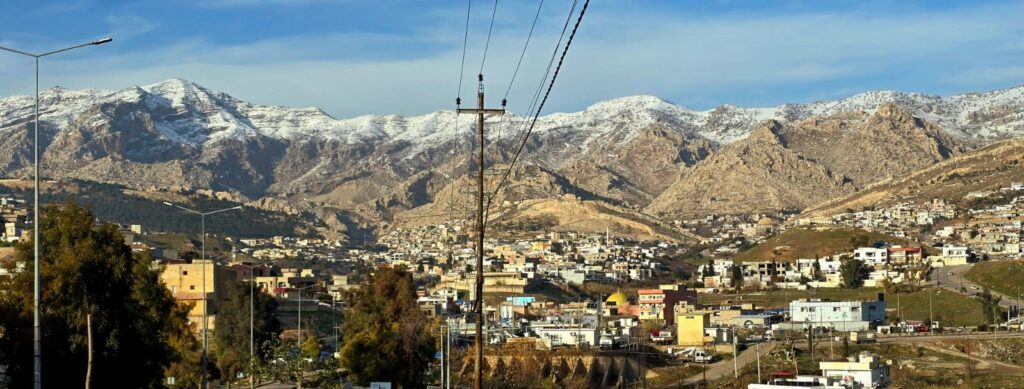 Elevated view of Akre, a picturesque hillside town in the Kurdistan Region of Iraq, with colorful homes built into the surrounding mountains.