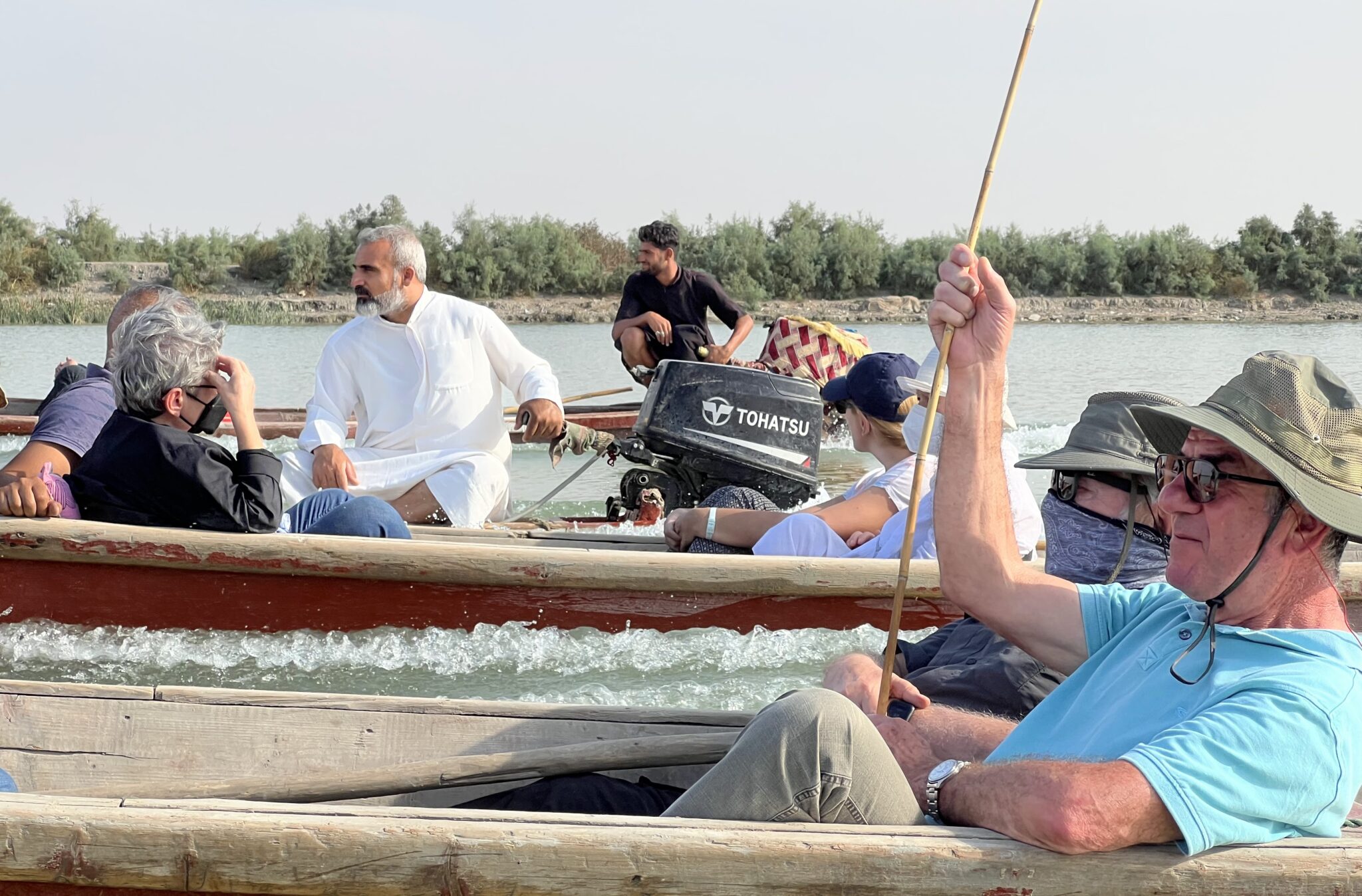 Visitors enjoying a traditional boat journey through the tranquil waterways and dense reed beds of the Mesopotamian Marshes in southern Iraq.