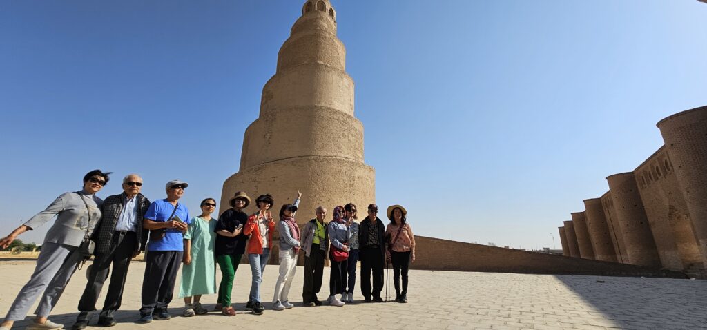 Group of tourists standing in front of the Great Mosque of Samarra and its iconic spiral minaret in Iraq, one of the most distinctive landmarks of the historic city